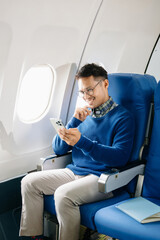 ￼Asian woman sitting in a seat in airplane and looking out the window going on a trip vacation travel concept.