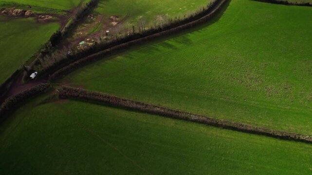 Aerial shot tilting up from fields and hedgerows to reveal countryside of Exmoor National Park