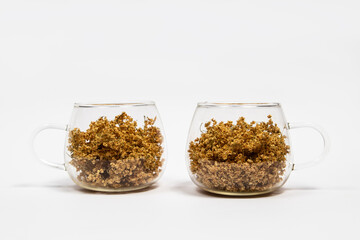 Dry elderberry flowers in glass cups on a white background