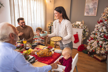 Young woman bringing dessert while having family Christmas dinner at home