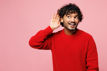 Young curious nosy smiling Indian man he wear red sweater casual clothes try to hear you overhear...