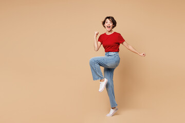 Full body young happy woman wear red t-shirt casual clothes doing winner gesture celebrate...