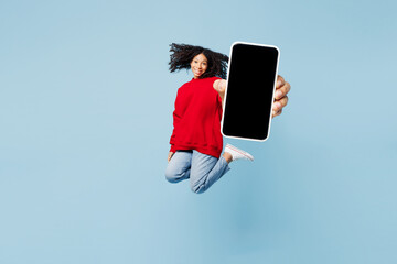 Full body little kid teen girl of African American ethnicity wear red sweatshirt jump high hold use...