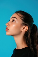 Fototapeta premium A young woman with a confident expression against a bright blue background, showcasing her unique beauty and style.