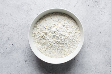 overhead view of All purpose flour in a bowl, top view of baking flour in a ceramic bowl