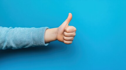 Close-up of a hand giving a thumbs up gesture against a blue background.