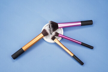 makeup brushes with coaster on blue background