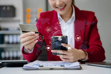 Business woman hand holding credit card and use laptop and smartphone in office.