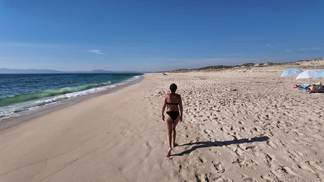A stunning summer day at Comporta beach, Portugal, featuring golden sand, clear blue skies, and ocean waves. 
