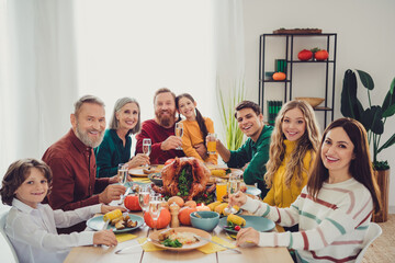Photo of positive happy people relatives celebrating thanksgiving day sitting eating drinking family gathering indoors room home