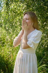 beautiful young artist in a white dress among the trees on the river bank