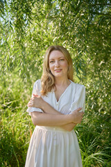 beautiful young artist in a white dress among the trees on the river bank