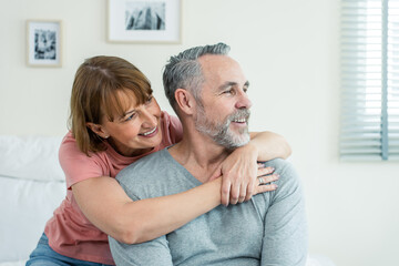Obraz premium Caucasian senior older couple sitting on bed then look outside window. 
