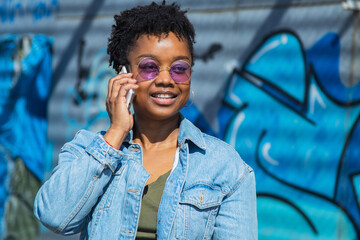 Smiling woman talking on smartphone on graffiti wall