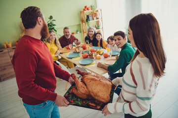 Photo of happy young people spouses hold table stuffed baked tasty traditional meat turkey...