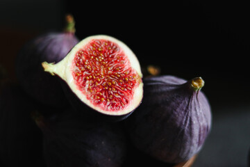 Close up of fresh ripe fig fruits in a wooden bowl on dark grey table 
