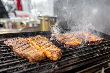 Close-up of juicy grilled steaks on a barbecue, with smoke rising. Perfect for summer cookouts, BBQ parties, and food-related themes. High-quality image showcasing delicious, well-cooked meat.
