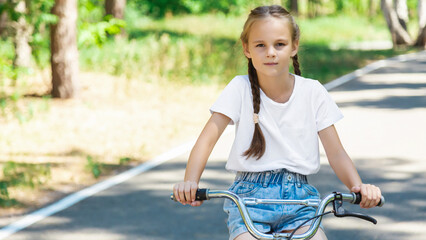Obraz premium cheerful child girl riding a bike in Park in the nature