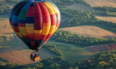 Obraz premium Hot air balloon flying over fields and trees.