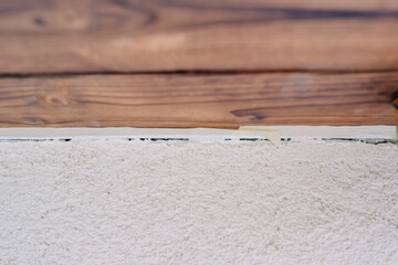 Close-up of a freshly plastered wall with wooden paneling above, showing the clean edge between materials during a renovation project.