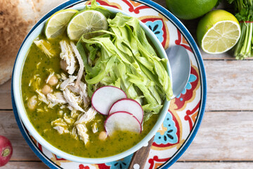 Traditional mexican green pozole soup on wooden table
