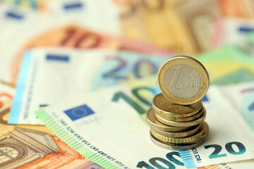 One euro coin lies on huge amount of different euro dollars banknotes