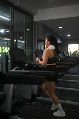 Full length of fit woman running on a treadmill at gym. Sports and healthy lifestyle concept