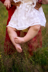 a baby girl strokes the fluffy grass with her tiny legs, the grass tickles