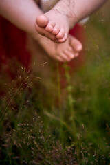 a baby girl strokes the fluffy grass with her tiny legs, the grass tickles