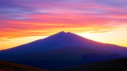 A majestic mountain range silhouetted against a vibrant sunset sky, with hues of pink, orange, and purple.