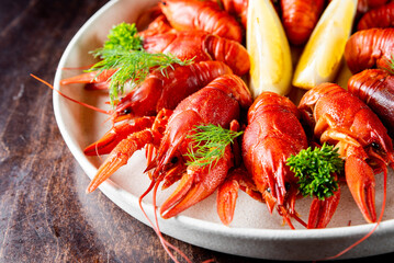 A close-up of a plate with cooked crayfish, garnished with fresh herbs and lemon slices, suggesting a delicious seafood meal. Perfect for culinary, food, and dining themes.