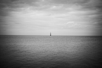 Old sailing ship at distant in silhouette against horizon over water at dusk in black and white