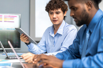 Diverse team of business professionals working on laptops during corporate meeting analyzing data and discussing project strategies, focused on collaboration, productivity and effective communication