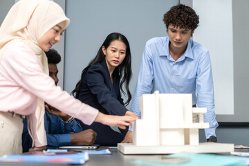 Architects engineers collaborating on building design project in modern office, diverse team of professionals female muslim architect and male engineers discussing architectural model of structure