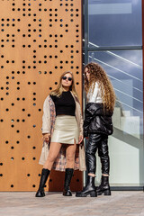 Two young women in casual clothes are standing on the street.