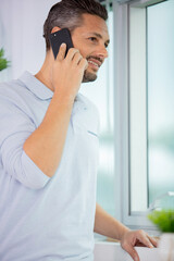 man stood by window using his smartphone