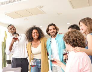 Joyful multi-racial friends having a conversation and laughing together at a dining table, smiling as they enjoy champagne in a warm and loving toast, sharing a moment of togetherness and celebration.