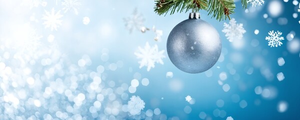 Winter holiday decoration featuring a silver ornament dangling from evergreen branches against a sparkling blue background