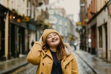 Fototapeta premium With a warm smile and cheerful demeanor, a young Irish girl stands in a lively city street, radiating happiness as she playfully adjusts her hat, surrounded by urban charm.