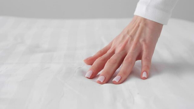 Woman running her hand over sheet, closeup