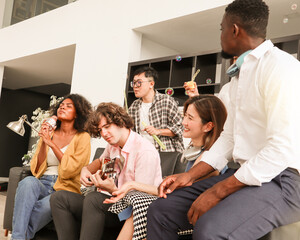 A group of multiracial teenagers is playing guitar and singing a song together while happily having fun blowing bubbles at the afternoon party. Recreational activity and celebration concepts.