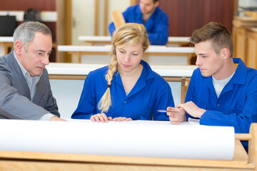carpenter with apprentices in workshop
