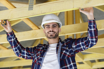 happy male carpenter working on beams