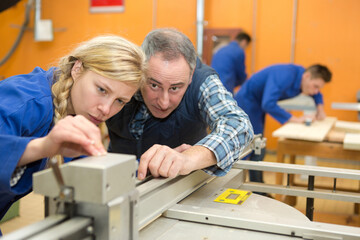 carpenter and young female apprentice working together in workshop