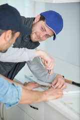 man assembling hinge on kitchen cupboard using screwdriver