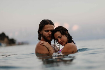 Fototapeta premium couple in love in water swim in the sea in the evening and love each other, long-haired couple.