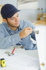 Fototapeta premium young man fitting wardrobe in kitchen cabinet