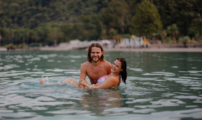 couple in love in water swim in the sea in the evening and love each other, long-haired couple.