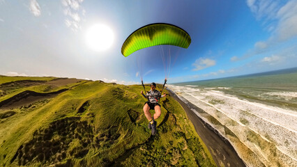 Extreme paragliding pilot soaring in the New Zealand beach at sunset. Adventure concept