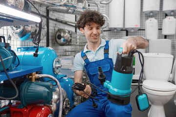 Fototapeta premium Plumber choosing water pump for heating systems at plumbing store